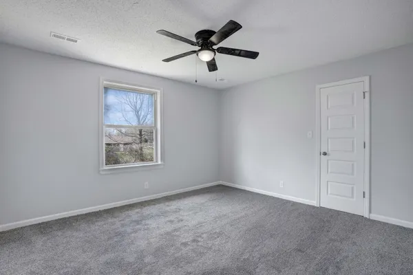 an empty room with ceiling fan and windows