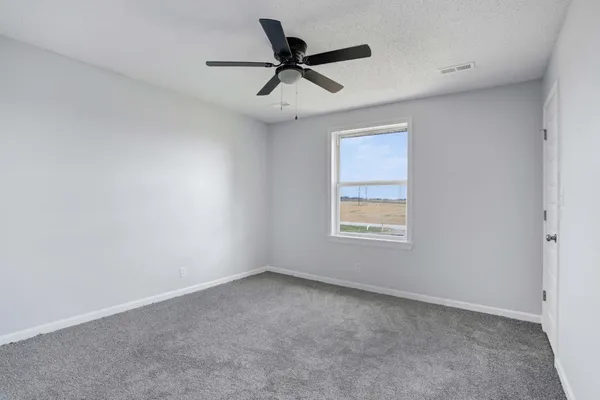 an empty room with a window and a ceiling fan