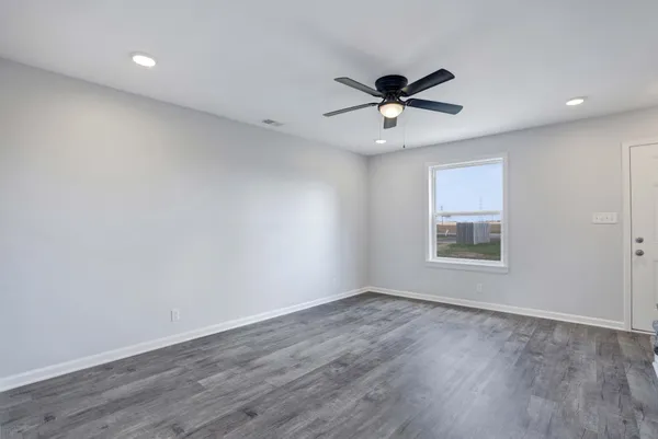 a view of a big room with wooden floor a ceiling fan and windows