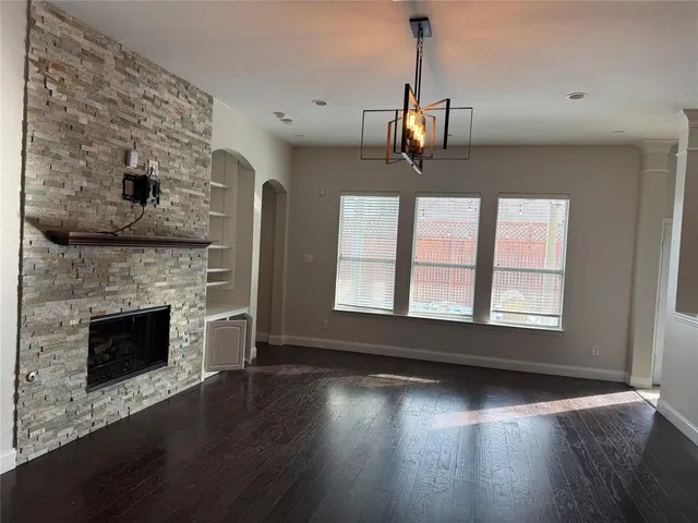 an empty room with wooden floor fireplace and windows