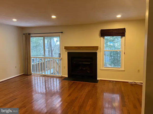 an empty room with wooden floor fireplace and windows