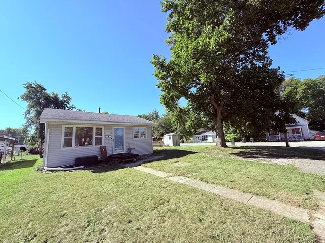 a view of a house with a yard and large trees