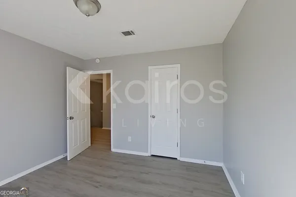 a view of an empty room with wooden floor and glass door