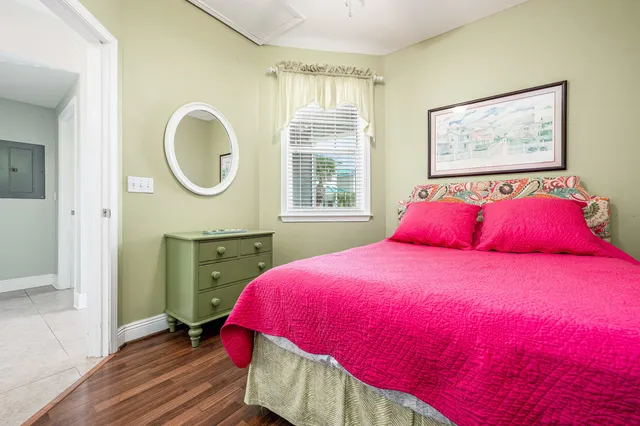 a bedroom with a bed a dresser with wooden floor