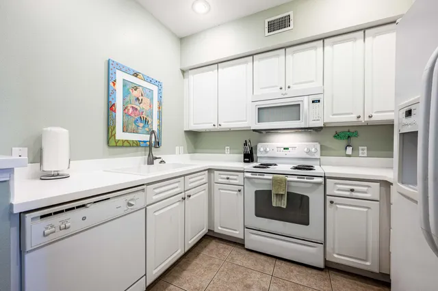 a kitchen with granite countertop white cabinets and white appliances