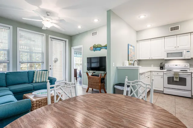 a large white kitchen with furniture a flat screen tv and a stove