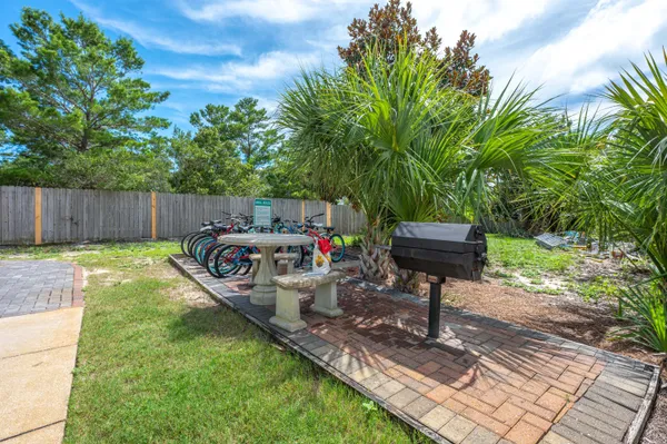 a view of a backyard with table and chairs potted plants and large tree