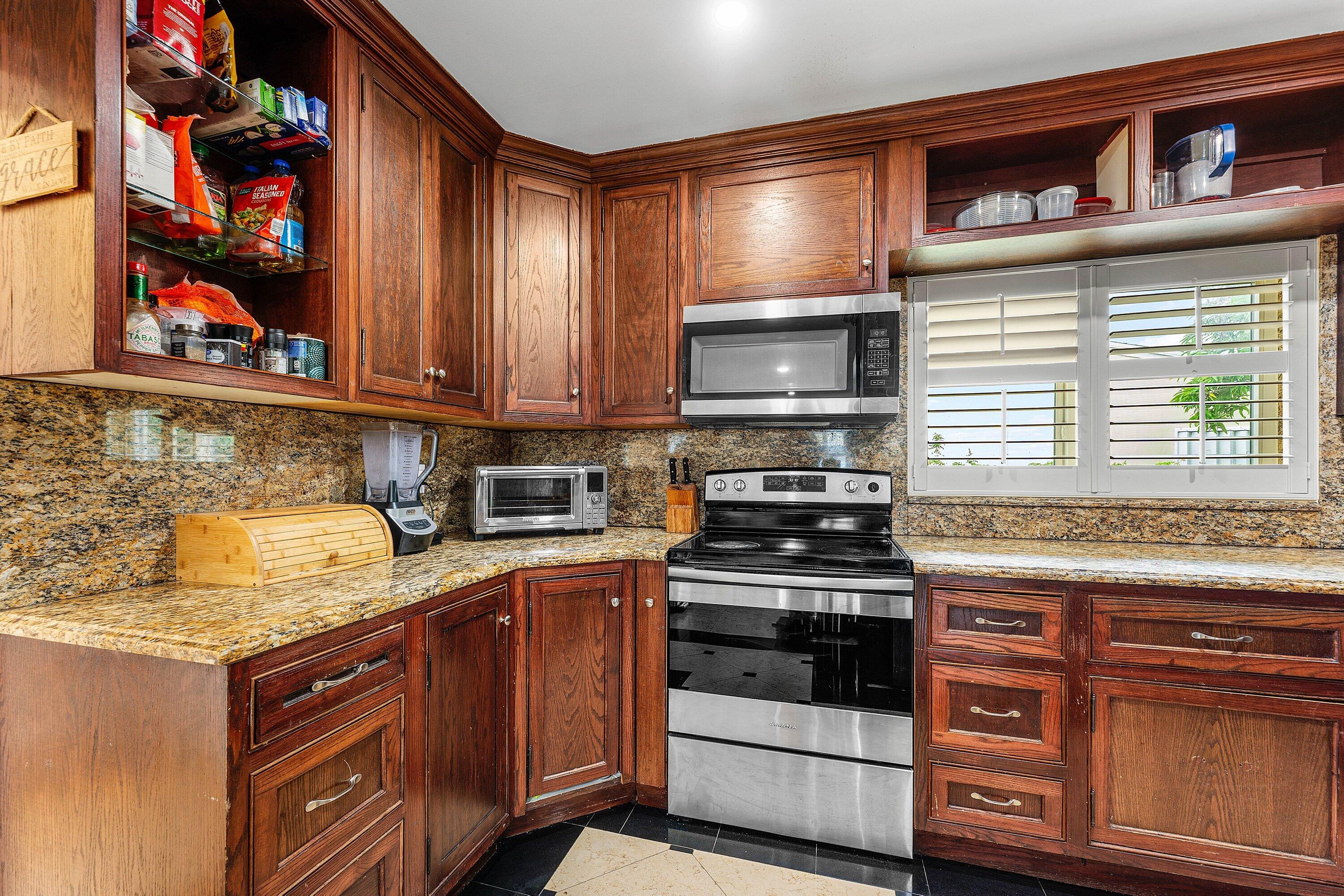 305 Southwest 3rd Street Boynton Beach, FL 33435 - Photo 12 of 36 a kitchen with stainless steel appliances granite countertop a stove and cabinets