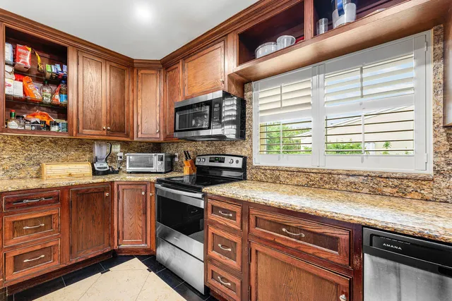 a kitchen with stainless steel appliances granite countertop wooden cabinets a stove a sink and dishwasher next to a window