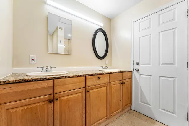 a bathroom with a granite countertop double vanity sink and a mirror