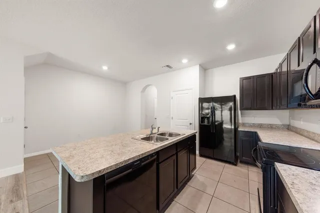a kitchen with stainless steel appliances kitchen island granite countertop a refrigerator a sink and a stove