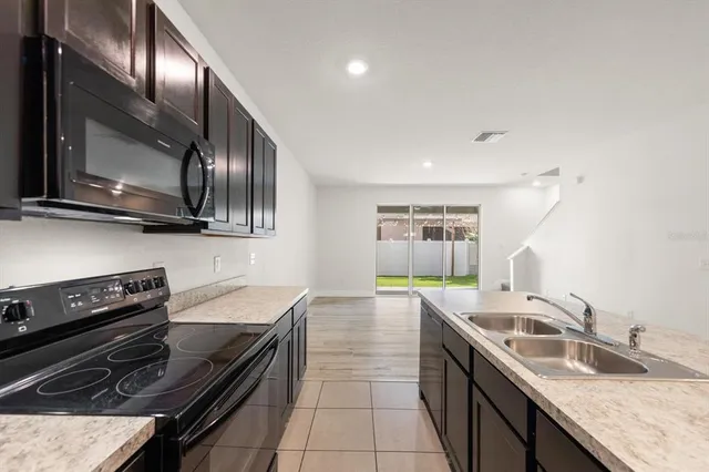 a kitchen with granite countertop stainless steel appliances a stove sink and microwave