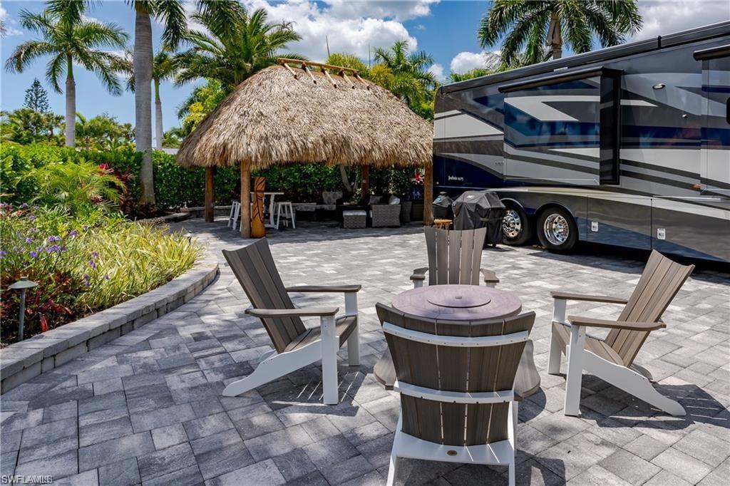 13526 Snook Circle Naples, FL 34114 - Photo 17 of 36 a view of a patio with table and chairs potted plants and palm trees