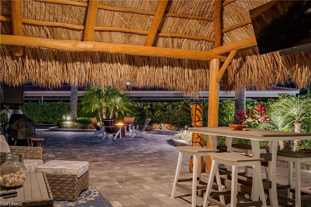13526 Snook Circle Naples, FL 34114 - Photo 29 of 36 a view of a patio with a table and chairs under an umbrella with a small yard