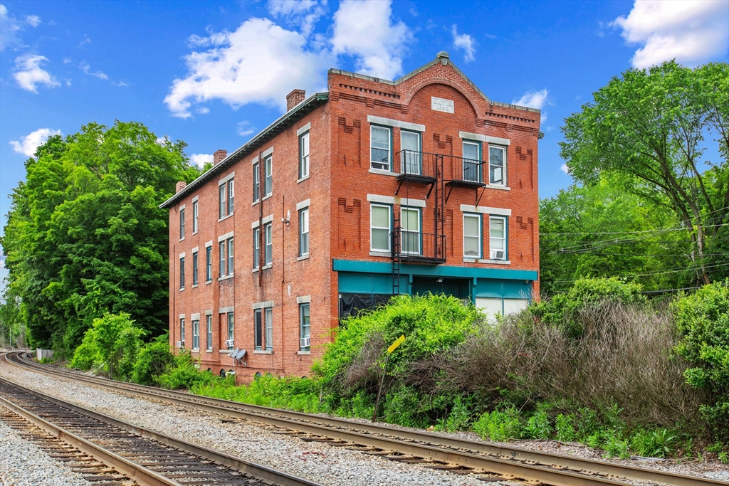 4 Davis Street Shirley, MA 01464 - Photo 3 of 18 a view of a big building in front of a yard with potted plants