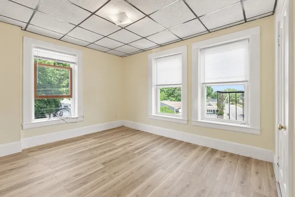 an empty room with wooden floor and windows