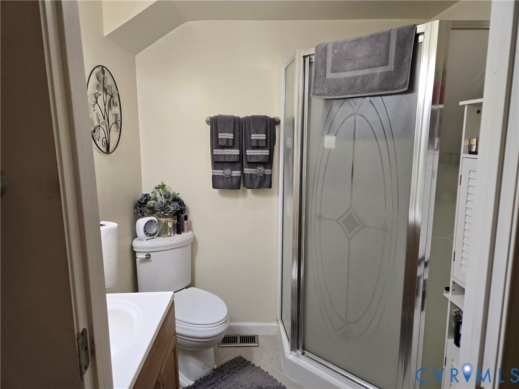 6883 Flat Rock Road Warfield, VA 23889 - Photo 16 of 25 a white toilet sitting next to a bathroom sink and a shower