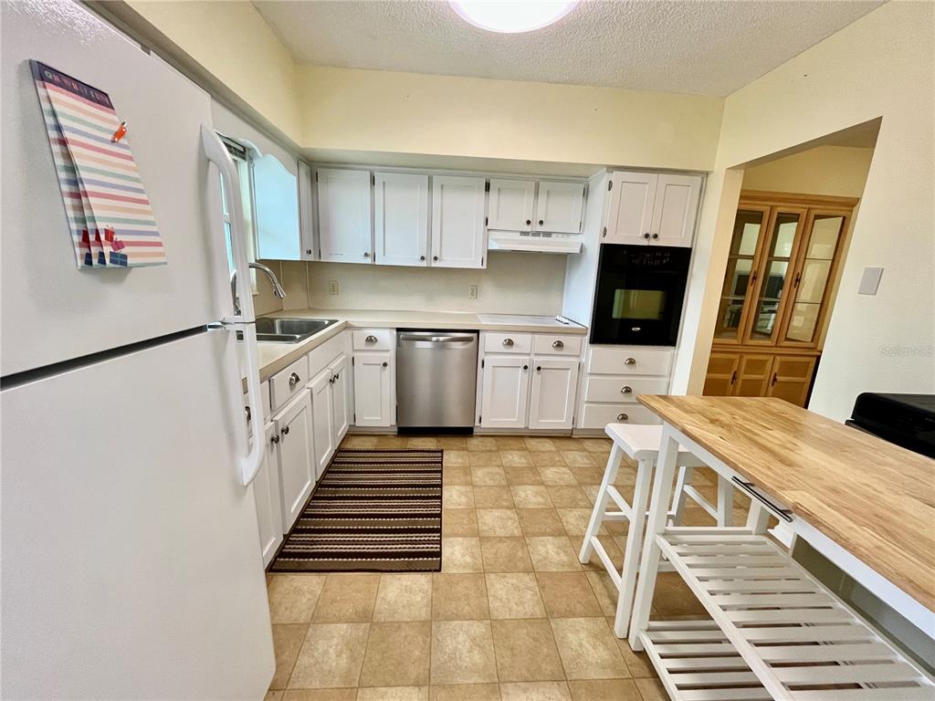 2292 Costa Rican Drive, Unit 22 Clearwater, FL 33763 - Photo 7 of 44 a kitchen with stainless steel appliances a stove top oven a sink a dining table and chairs