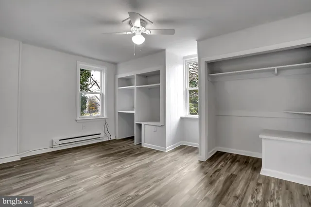 an empty room with wooden floor chandelier fan and windows