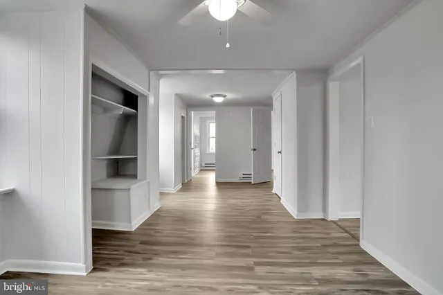 a view of a hallway with wooden floor and a kitchen space