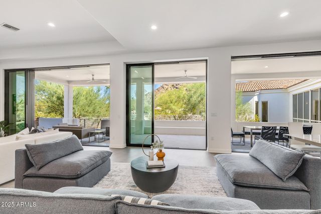 a living room with furniture large windows and white walls