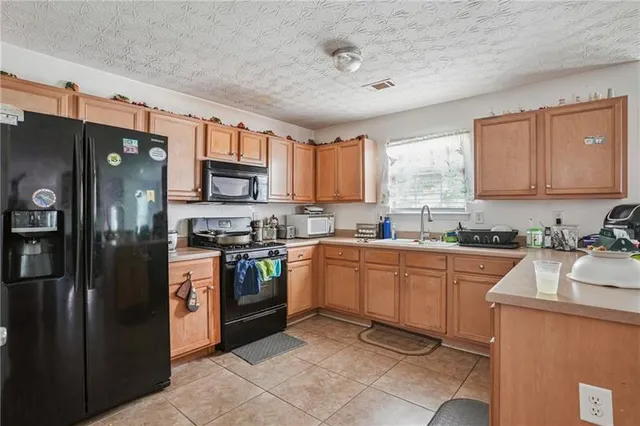 a kitchen with granite countertop a refrigerator stove top oven and sink