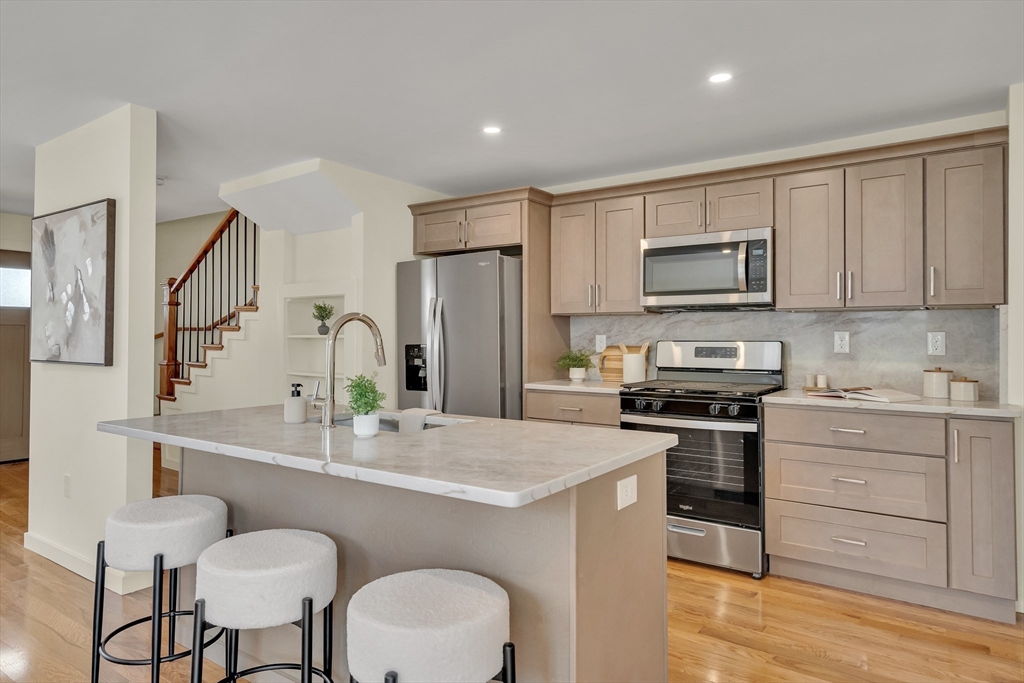 56 Riverview Street Dedham, MA 02026 - Photo 7 of 29 a kitchen with stainless steel appliances a stove a sink a refrigerator white cabinets and wooden floor
