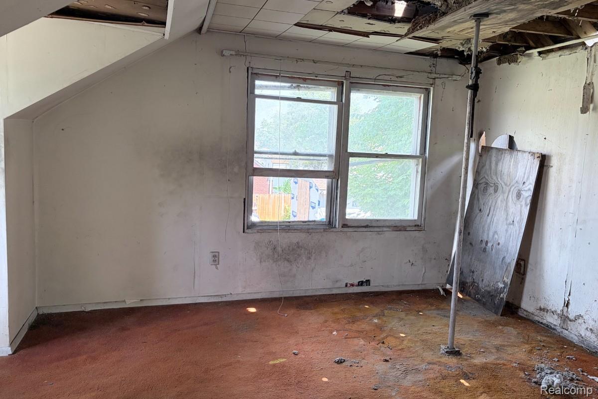 13536 Ashton Road Detroit, MI 48223 - Photo 7 of 9 Room featuring a double-hung window, sloped ceiling, and carpeted flooring
