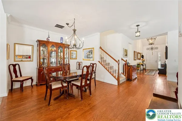 a dining room with wooden floor a chandelier a wooden table and chairs