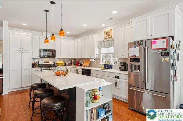 a kitchen with a refrigerator a stove and white cabinets with wooden floor