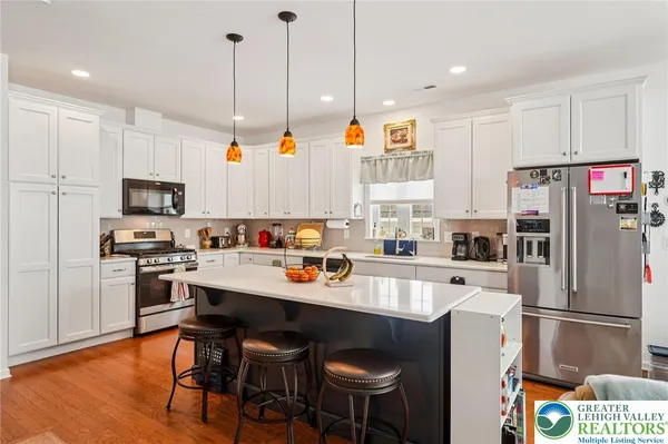 a kitchen with stainless steel appliances granite countertop a refrigerator a stove a sink a dining table and chairs with wooden floor