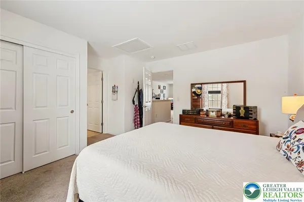 a large bedroom with a bed and a lamp on dresser