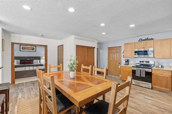 a dining hall with stainless steel appliances granite countertop a stove a dining table and chairs