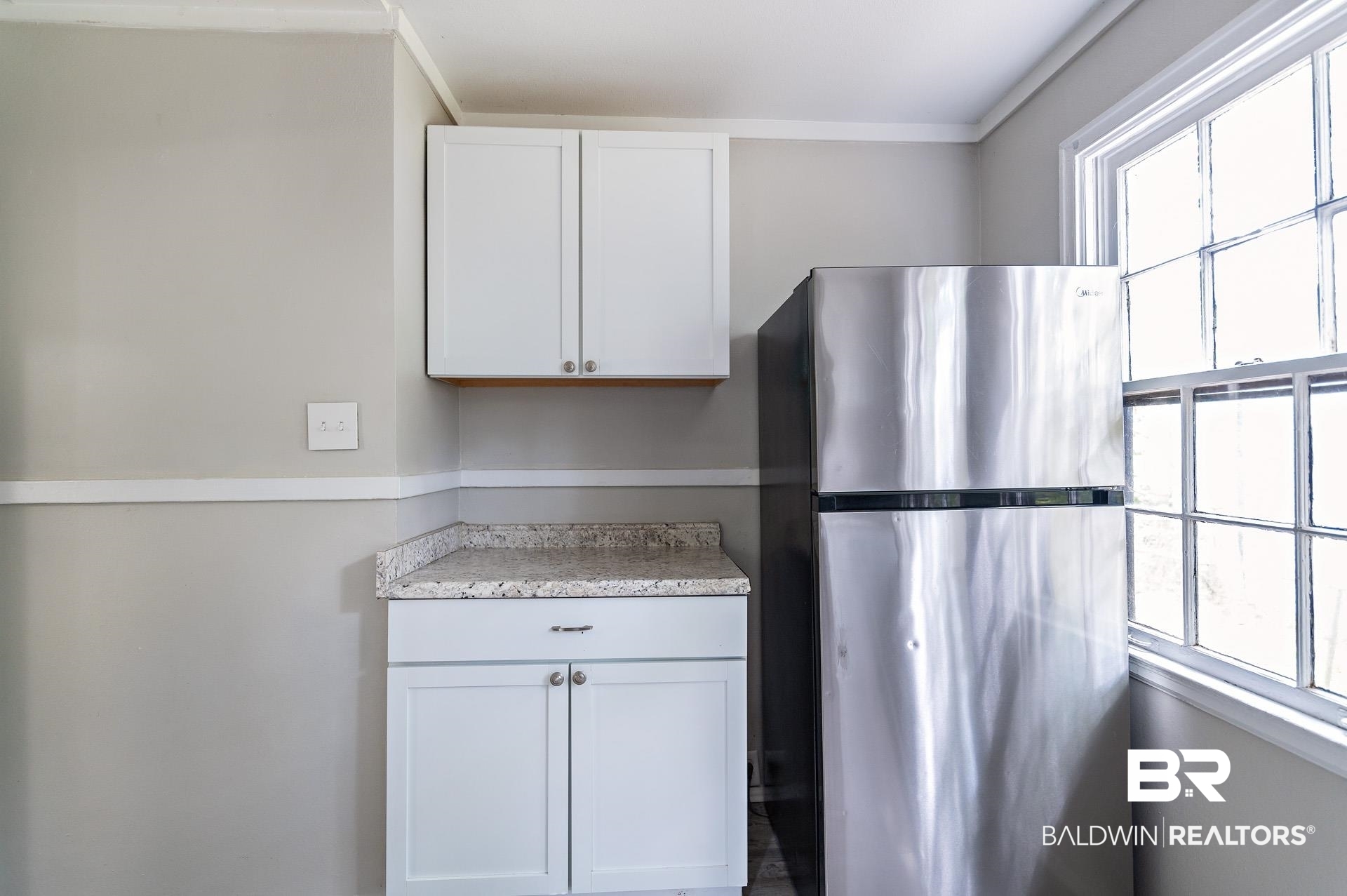 1869 Mott Drive West Mobile, AL 36617 - Photo 12 of 34 Kitchen with white cabinetry, light countertops, and freestanding refrigerator