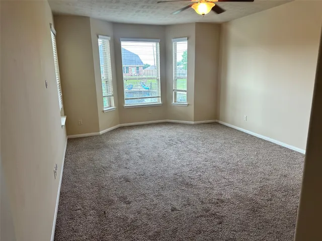 an empty room with windows and chandelier fan