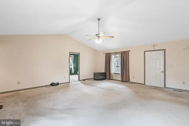 an empty room with chandelier fan and windows
