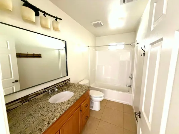 a bathroom with a granite countertop sink mirror vanity and toilet