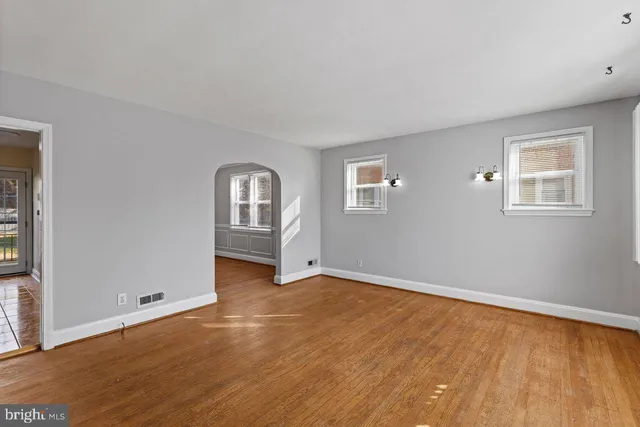 a view of an empty room with window and wooden floor