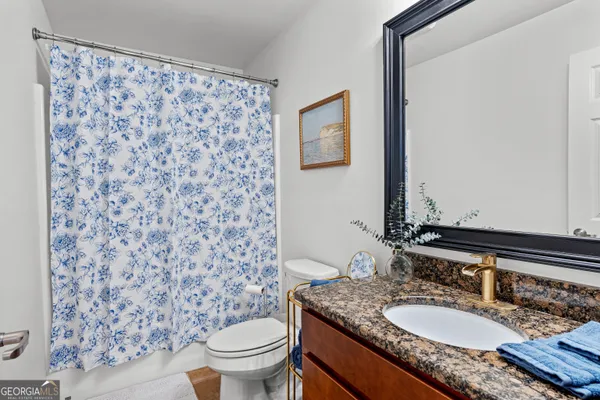 a bathroom with a granite countertop sink a toilet and a mirror