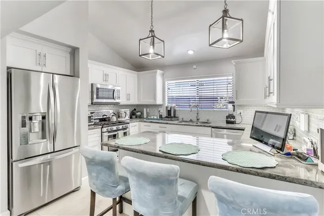 a kitchen with stainless steel appliances granite countertop a refrigerator a stove a sink a stove a dining table and chairs with wooden floor