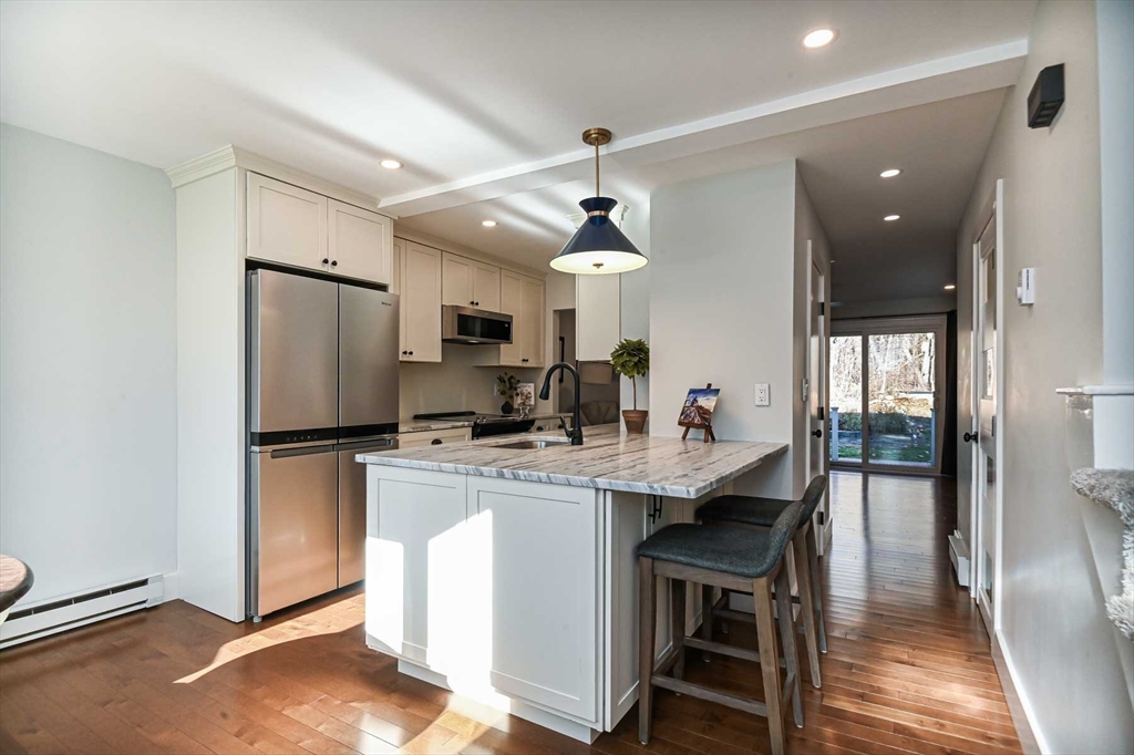 1 Acadia Kimball Road, Unit 1 Amesbury, MA 01913 - Photo 8 of 21 a kitchen with stainless steel appliances a dining table chairs refrigerator and microwave