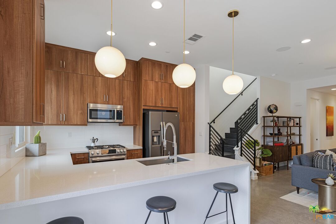 504 Paragon Loop Palm Springs, CA 92262 - Photo 21 of 45 a kitchen with stainless steel appliances a stove a sink a oven a dining table and chairs with wooden floor