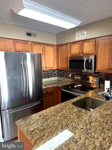 a kitchen with stainless steel appliances granite countertop a refrigerator sink and stove