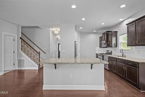 a view of a kitchen with granite countertop a stove top oven a sink and dishwasher with wooden floor