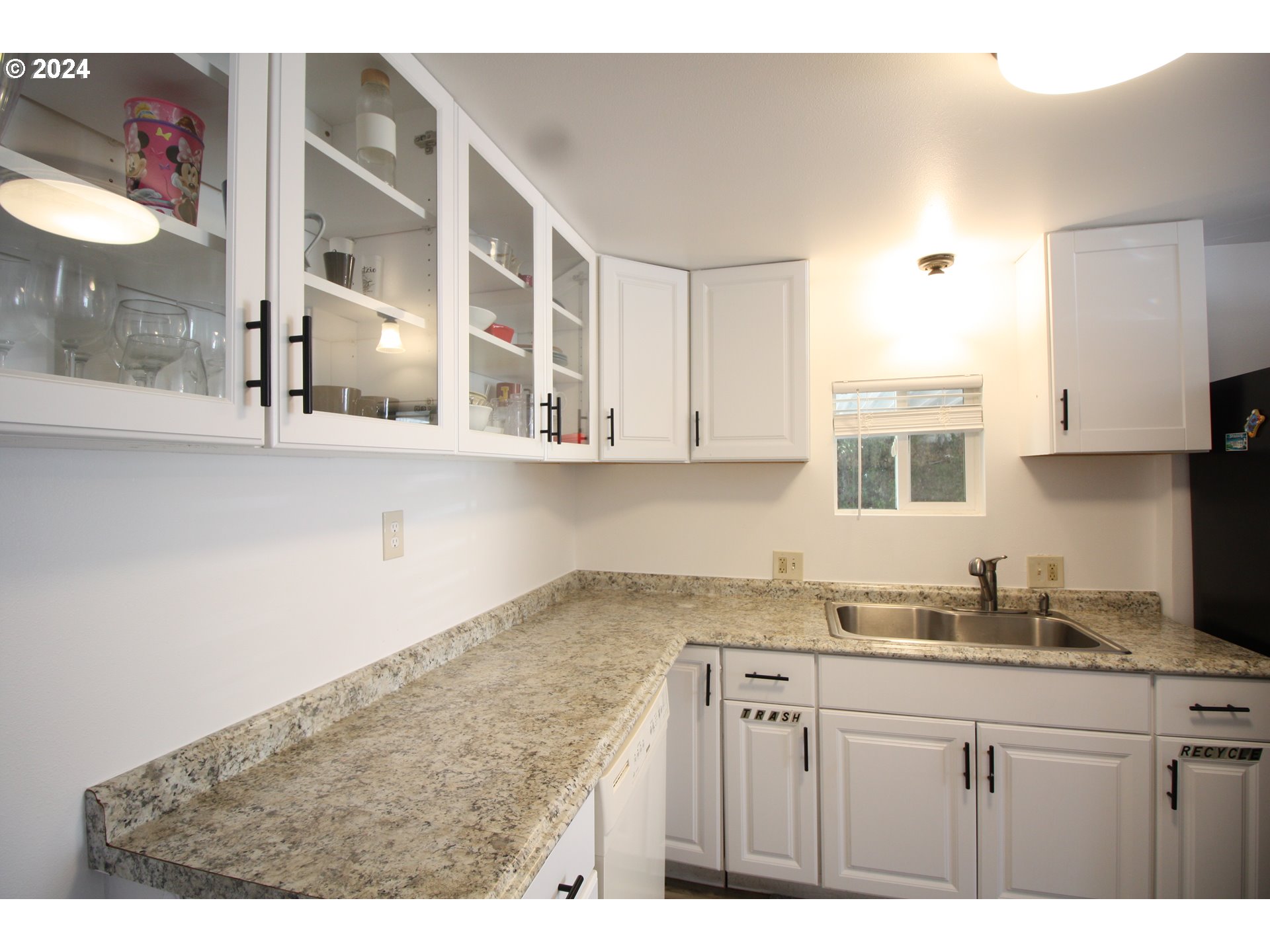 12450 Southwest Fischer Road, Unit 143 Portland, OR 97224 - Photo 4 of 11 a kitchen with granite countertop a sink cabinets and wooden floor