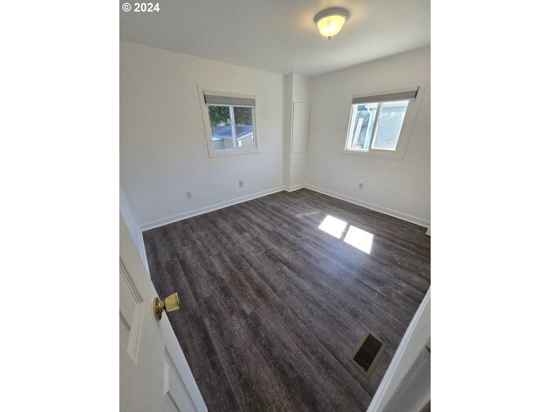 12450 Southwest Fischer Road, Unit 143 Portland, OR 97224 - Photo 7 of 11 a view of an empty room with wooden floor and a window