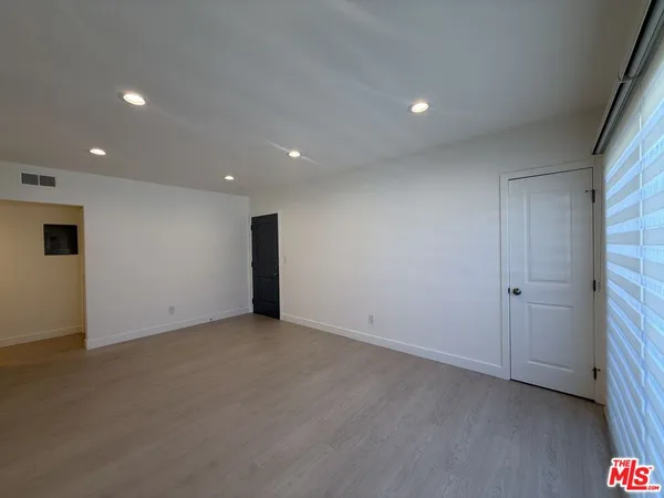 a view of an empty room with wooden floor and closet