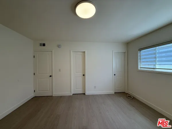 en empty room with wooden floor and windows