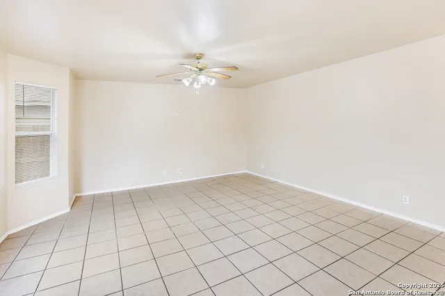 a view of an empty room and chandelier fan