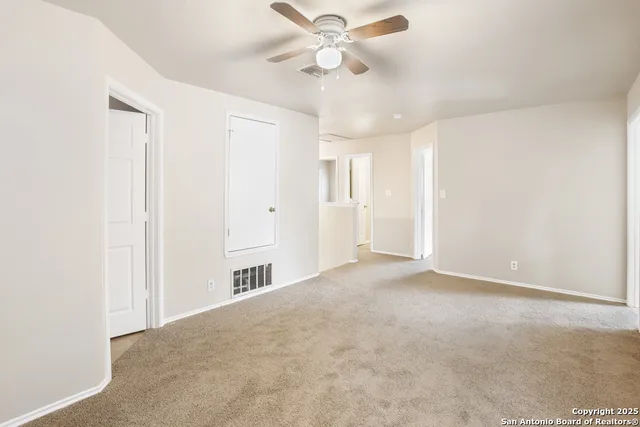 an empty room with windows and fan